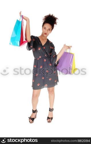 A happy multi-racial woman standing and holding her shopping bags high up, smiling into the camera with her curly blackhair, isolated for white background