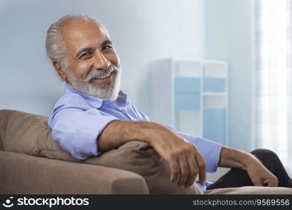 A HAPPY OLD MAN LOOKING AT CAMERA WHILE RELAXING AT HOME