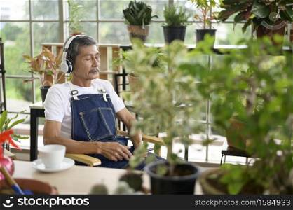 A happy senior asian retired man listening to music and enjoying leisure activity in garden at home.. Happy senior asian retired man listening to music and enjoying leisure activity in garden at home.