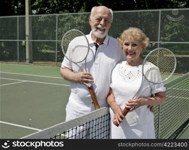 A happy senior couple stays active by playing tennis. Room for Text