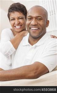 A happy smiling African American man and woman couple with perfect teeth, in their thirties sitting at home