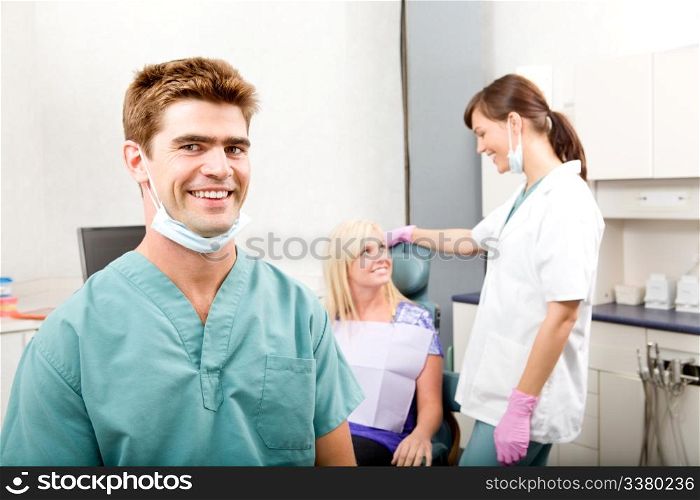 A happy smiling dentist at a clinic with an assistant and patient