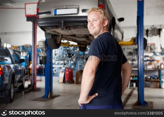 A happy smiling mechanic in an autio repair shop, looking at the camera