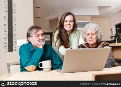 A happy teenage girl and her grandparents using a laptop