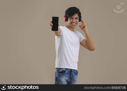 A HAPPY TEENAGER ENTHUSIASTICALLY SHOWING MOBILE PHONE