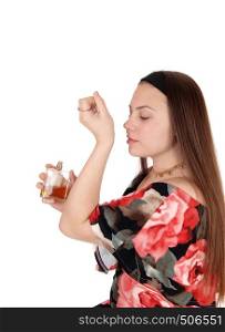 A happy teenager girl tried a new perfume if she will like it for herselfin a summer dress, isolated for white background