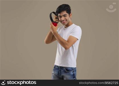 A HAPPY TEENAGER HOLDING WIRELESS HEADPHONES WHILE LOOKING AT CAMERA
