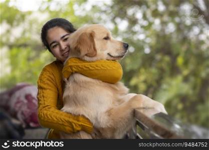 A HAPPY TEENAGER LOOKING AT CAMERA WHILE HUGGING PET DOG