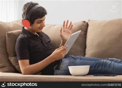 A HAPPY TEENAGER RELAXING AND USING DIGITAL TABLET