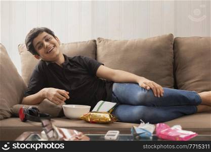 A HAPPY TEENAGER RELAXING ON SOFA AND ENJOYING IN FRONT OF CAMERA