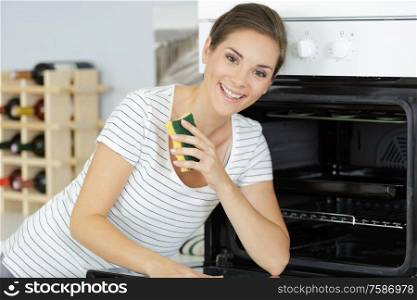 a happy woman cleaning oven