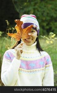 A happy woman holding an autumn/fall leaf