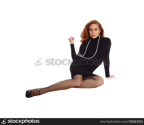 A happy woman in a black dress and long brunette hair sitting onthe floor, isolated for white background.