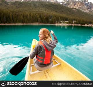 A happy woman in a canoe on a clear glacial lake