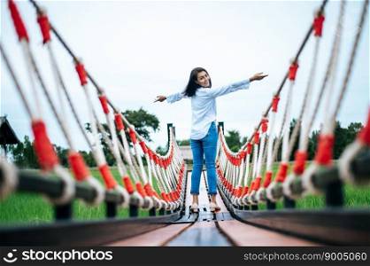 A happy woman on a wooden bridge in a green meadow on a sunny day. Happy, health, travel, lifestyle concept