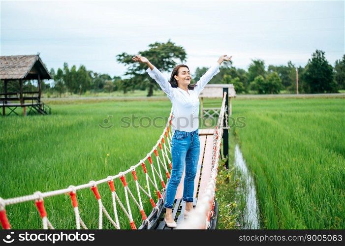 A happy woman on a wooden bridge in a green meadow on a sunny day. Happy, health, travel, lifestyle concept