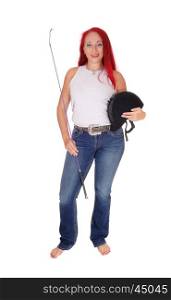 A happy woman with her rider helmet and whip, with long red hairstanding isolated for white background.