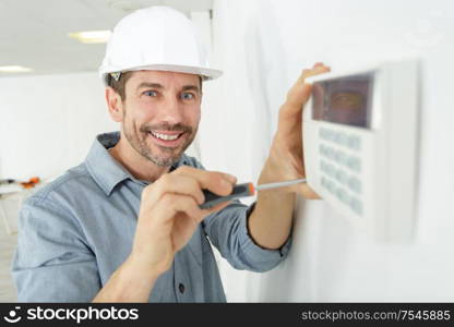 a happy worker fixing thermostat