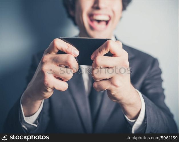 A happy young businessman is laughing about something on his smartphone