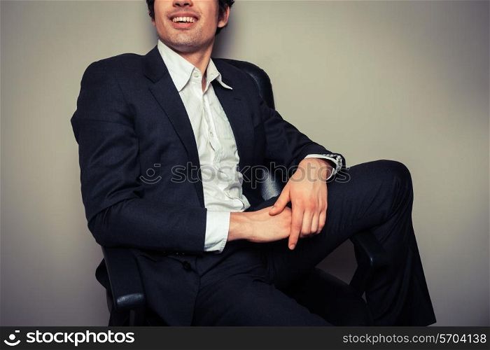 A happy young businessman is sitting in a relaxed pose