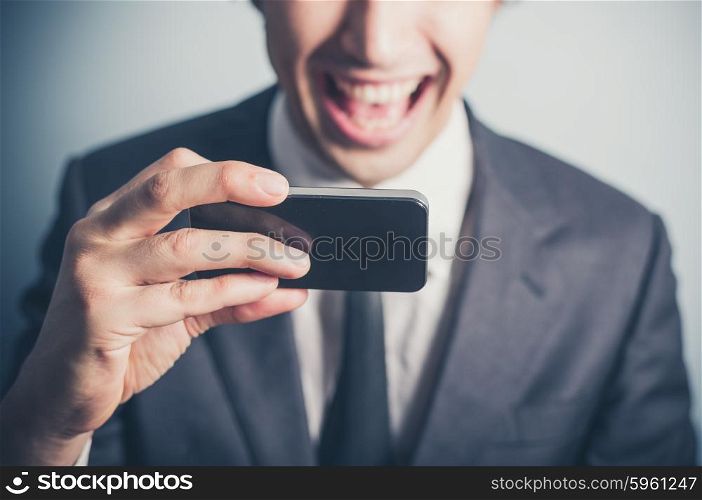 A happy young businessman is using his smartphone