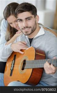 a happy young couple playing the guitar
