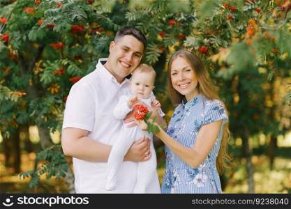 A happy young family with a cute little son in the summer in the park