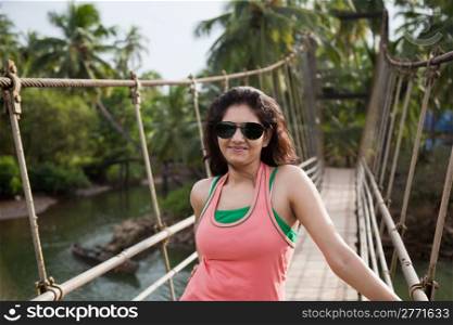 A happy young girl enjoying nature while relaxing on hanging bridge.