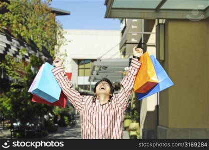 A happy young man carrying shopping bags at an outdoor shopping mall
