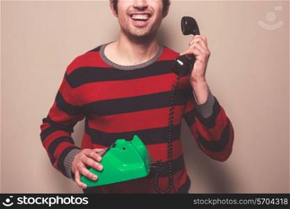 A happy young man is answering the telephone