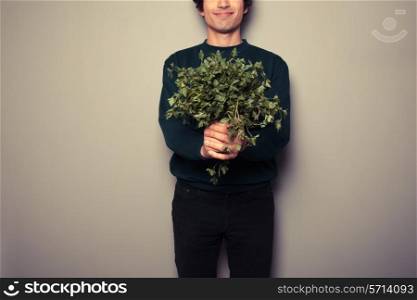 A happy young man is holding a big bunch of fresh parsley