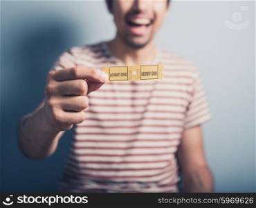 A happy young man is holding two cinema tickets