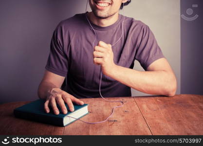 A happy young man is listening to an audio book