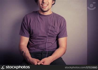 A happy young man is listening to music through his earphones