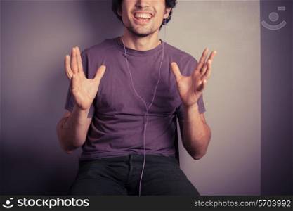 A happy young man is listening to music through his earphones
