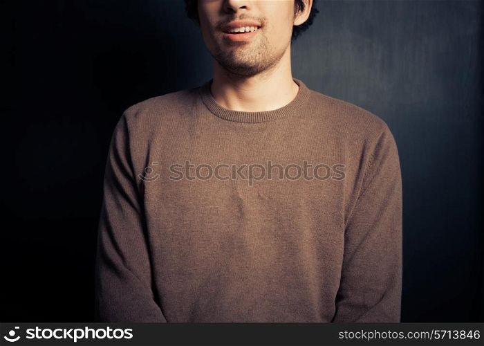 A happy young man is sitting against a black background