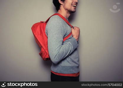 A happy young student is wearing a red backpack and is smiling