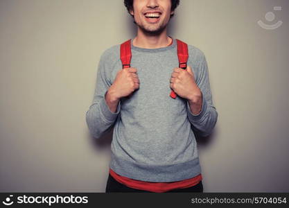 A happy young student is wearing a red backpack and is smiling