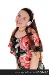 A happy young teenage girl is listening to the music from her head phone and smiling in a summer dress, isolated for white background