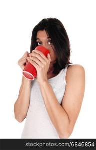 A happy young woman in a white t-shirt holding a red coffeemug on her mouth, isolated for white background.