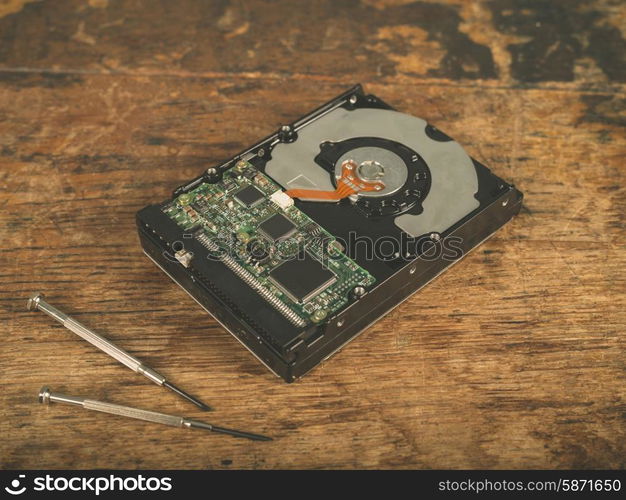 A harddrive and a screwdriver on a wooden desk