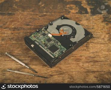 A harddrive and a screwdriver on a wooden desk