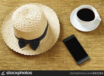 A hat with a cup of coffee, and a phone placed on the work area.