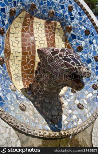 a head of a saurian made of tiles and stones styled by antonio gaudie in park guell