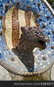 a head of a saurian made of tiles and stones styled by antonio gaudie in park guell