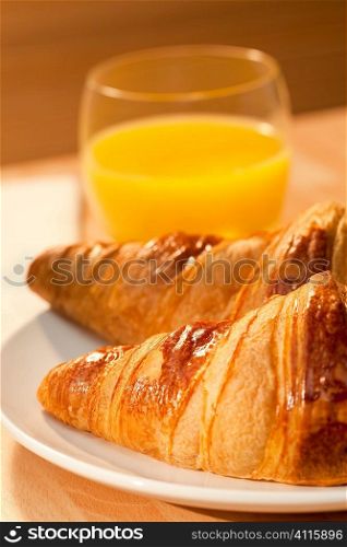A healthy continental breakfast of croissant pastries, orange juice, Illuminated with golden early morning sunshine.
