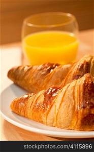 A healthy continental breakfast of croissant pastries, orange juice, Illuminated with golden early morning sunshine.