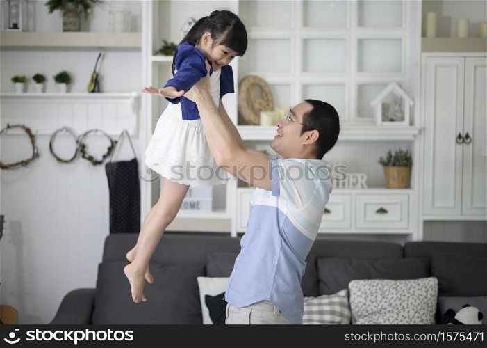 A healthy father is holding happy cute daughter flying and playing plane together at home on weekends, family concept.