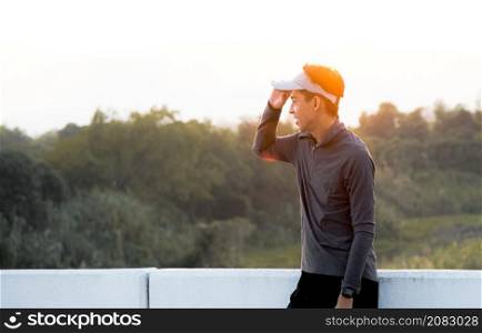 A healthy teenage boy resting on a bridge after jogging in the morning. Young man exercising outdoors.