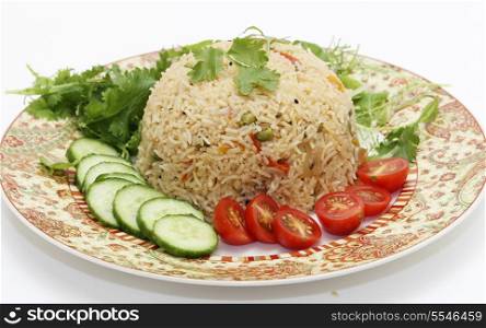 A healthy tomato (thakkali) biriyani with a salad of cucumber, cherry tomatoes and some fresh leaves. This biryani, which incorporates onion, peas and a capsicum ball pepper, is a South Indian dish.